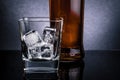 Close-up of whiskey with ice cubes in glass near bottle on black background, cold atmosphere Royalty Free Stock Photo