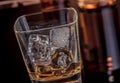 Close-up of whiskey with ice cubes in glass near bottle on black background, warm atmosphere Royalty Free Stock Photo