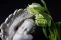 Close up of a white angel with tulip flowers on a dark background. Moment of grief at the end of a life. Last farewell. Funeral co