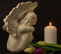 Statue of sad angel with tulip flowers as symbol of pain, fear and end of life. Remembrance concept Royalty Free Stock Photo