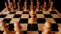Close up of white and black chess pieces on board. Selective focus on first move of white pawn on chessboard. Concept of