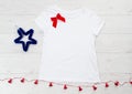 Close up white blank template t shirt with copy space and Christmas Holiday concept. Top view mockup t-shirt and red bow on white