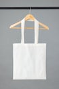 Close up of white canvas bag hanging on wooden clothes hanger with copy space on grey background Royalty Free Stock Photo