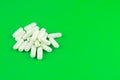 Close up white capsules on lime green background with copy space. Focus on foreground, soft bokeh. Pharmacy drugstore concept Royalty Free Stock Photo