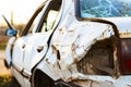 Close-up of a white car with significant rust and damage, highlighting the dented side panel and broken tail light, depicting negl Royalty Free Stock Photo