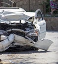 Close up of a white car wrecked during a car accident. Damaged front bumper, engine, headlights