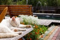 Close up of a white cat lying asleep on a wooden bench on the background of a fountain. Royalty Free Stock Photo