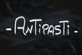 White chalk ANTIPASTI word over black chalkboard