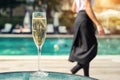 Close-up white champagne or prosecco glass against poolside at luxury resort hotel during vacation. Sparkling wine with rising Royalty Free Stock Photo