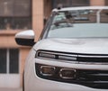 A close-up of a white Citroen C5 aircross SUV`s right HELLA LED headlights and turn signal windows