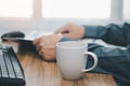 Close up white coffee cup and a man reading a newspaper on the work table Royalty Free Stock Photo