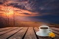 Close up white coffee cup on wood table and view of sunset or sunrise background Royalty Free Stock Photo