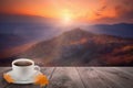 Close up white coffee cup on wood table and view of sunset or sunrise background Royalty Free Stock Photo