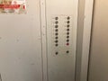 Close-up of a white control panel with labeled buttons and switches, including a red button The image is focus-pulled