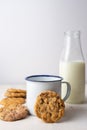 Close-up of white cup with chocolate chip cookies and bottle of milk, on table and white background Royalty Free Stock Photo