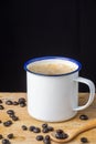 Close-up white cup with coffee, coffee beans and wooden spoon, on rustic table and black background Royalty Free Stock Photo