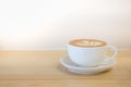 Close up of white cup of hot coffee latte with milk foam heart shape art on wooden table and copy space Royalty Free Stock Photo