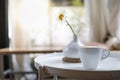 Close up of white cup of hot coffee latte with milk foam on round table with vase of flower in restaurant Royalty Free Stock Photo