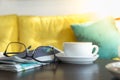 Close up of white cup of hot coffee latte with newspaper and reading glasses on wooden table in restaurant Royalty Free Stock Photo