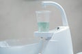 Close up of white dentist spittoon and plastic cup with light green water. Royalty Free Stock Photo