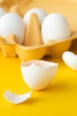 Close up of white eggs in the carton brown box on the yellow background. Macro shot of broken egg with white shell. Copy space for Royalty Free Stock Photo