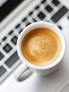Close up of a white espresso cup filled with aromatic coffee, placed on a computer keyboard, symbolizing work break and Royalty Free Stock Photo