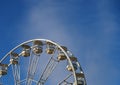 Close up of a white ferris wheel with enclosed gondola cars against a bright blue sky Royalty Free Stock Photo