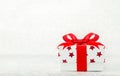 Close up of white gif box with red star pattern and red ribbon bow on bokeh background