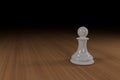 Close up of a white, glass, chess pawn on a wooden surface Royalty Free Stock Photo