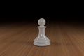 Close up of a white, glass, chess pawn on a wooden surface Royalty Free Stock Photo