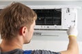 Portrait of a male technician repairing an air conditioner with a screwdriver