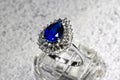 close-up white gold jewelry ring with a large blue pear-cut sapphire and diamonds on a gray background Royalty Free Stock Photo