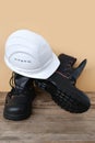 Close-up of white hardhat, pair of new black work boots made of leather with reinforced cape on old wooden boards, concept of Royalty Free Stock Photo