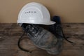 Close-up of white hardhat, pair of scratched, dirty black work boots with laces on old wooden boards, concept of special Royalty Free Stock Photo