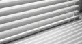 Close up of white horizontal window blinds casting striped shadows on a surface Royalty Free Stock Photo