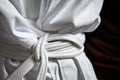 close-up of a white karate belt tied around a gi