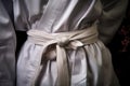 close-up of a white karate belt tied around a gi