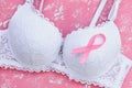 Close-up of white lace bra with breast cancer awareness ribbon on a pink background with white spots. Pink ribbon of cancer Royalty Free Stock Photo