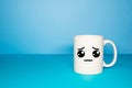 Close-up of a white mug on a blue background looking sad. Royalty Free Stock Photo