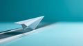 Close-up of white paper airplane on a blue surface with a blurred blue background, symbolizing creativity and innovation Royalty Free Stock Photo