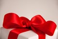 Close up of white paper gift box with a red satin ribbon bow on bright background. Holidays greeting cards and Christmas shopping Royalty Free Stock Photo