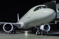 Close-up a white passenger aircraft at the jetway on an airport night apron