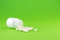 Close up white pill bottle with spilled out capsules on green background with copy space. Focus on foreground, soft bokeh. Pharmac Royalty Free Stock Photo