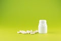 Close up white pill bottle with spilled out capsules on pear yellow background with copy space. Focus on foreground, soft bokeh. P Royalty Free Stock Photo