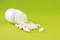 Close up white pill bottle with spilled out capsules on pear yellow background with copy space. Focus on foreground, soft bokeh. P Royalty Free Stock Photo