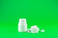 Close up white pill bottle with spilled out pills and capsules in cap on lime green background with copy space. Focus on foregroun Royalty Free Stock Photo