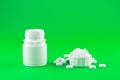 Close up white pill bottle with spilled out pills and capsules in cap on lime green background with copy space. Focus on foregroun Royalty Free Stock Photo