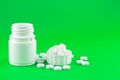 Close up white pill bottle with spilled out pills and capsules in cap on lime green background with copy space. Focus on foregroun Royalty Free Stock Photo