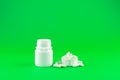 Close up white pill bottle with spilled out pills and capsules in cap on lime green background with copy space. Focus on foregroun Royalty Free Stock Photo