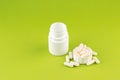 Close up white pill bottle with spilled out pills and capsules in cap on pear yellow background with copy space. Focus on foregrou Royalty Free Stock Photo